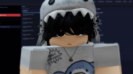 Animated character with black hair wearing gray shark hood sitting at computer