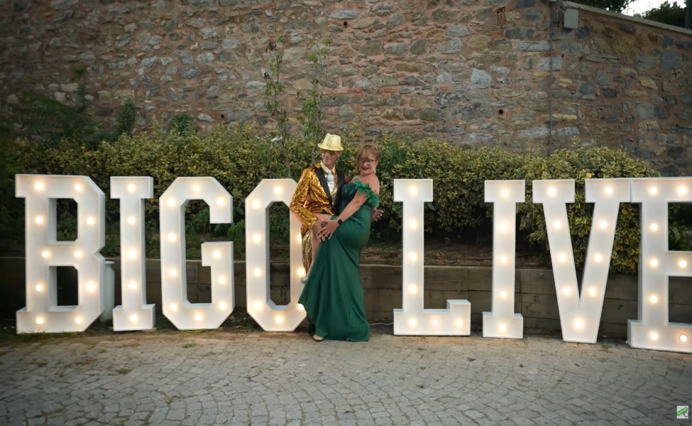 Couple posing with large illuminated BIGO LIVE letters at outdoor event venue